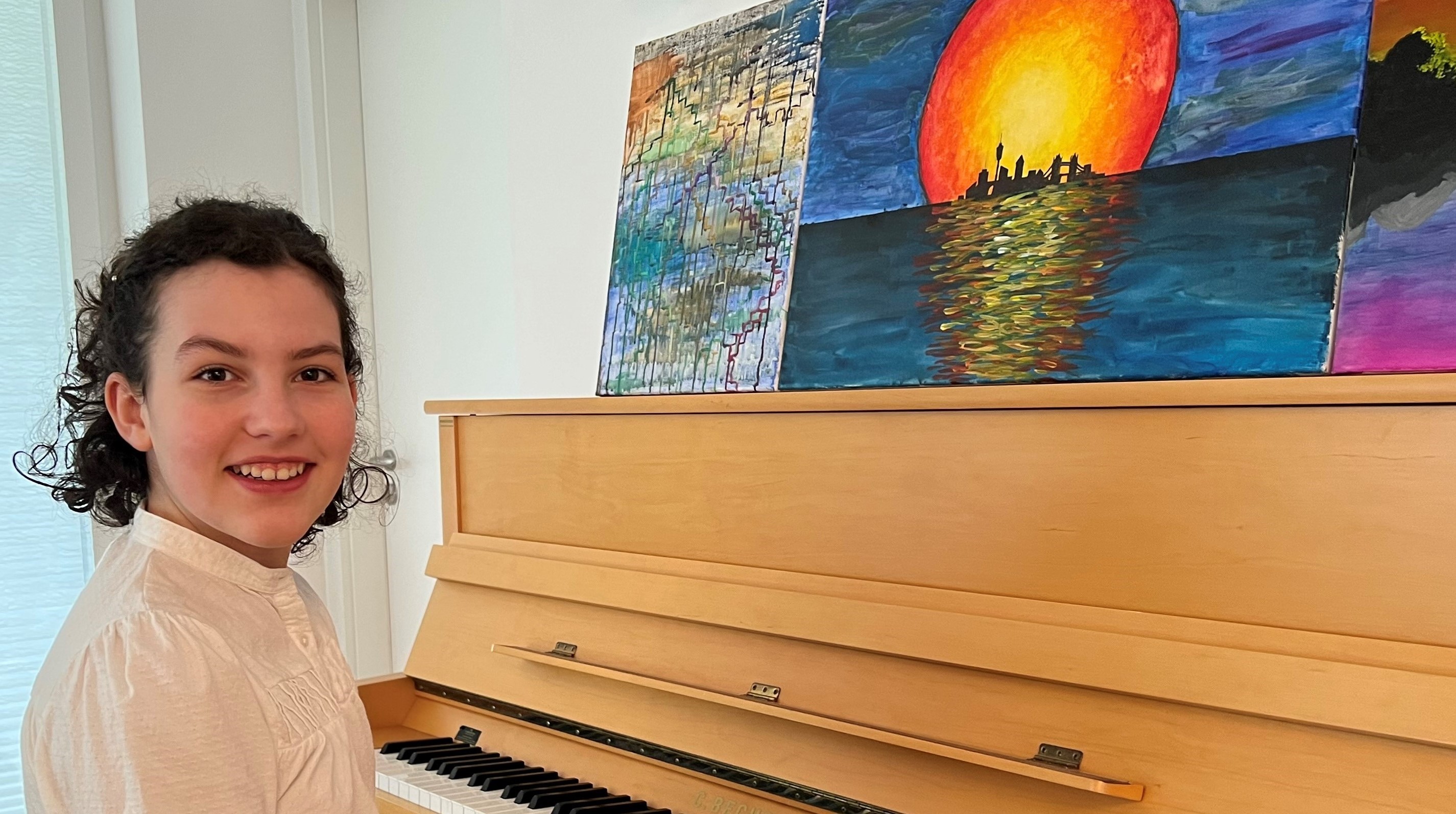 Foto Helen Zoe Friedrich Grossl am Klavier mit selbst gemalten Bildern Mai 2022
